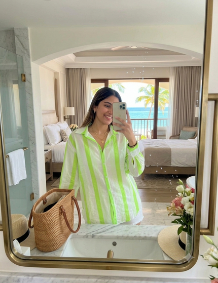 Sagar hill road relaxed cotton shirt with neon green vertical stripes, button-down front, worn by a woman in a hotel