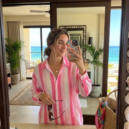 Sagar hill road relaxed cotton shirt with pink and white vertical stripes, worn by a woman in a beach resort mirror.