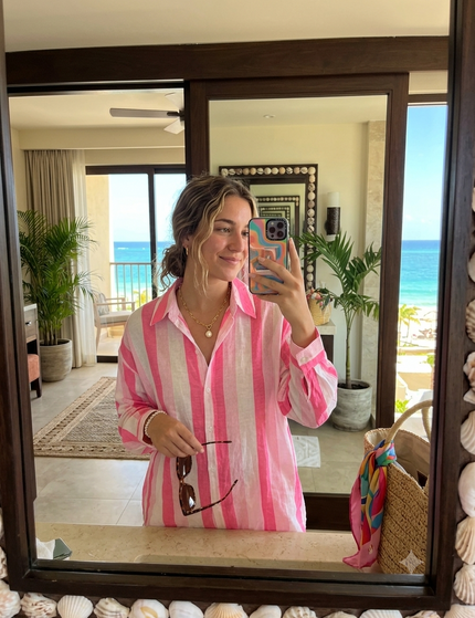 Sagar hill road relaxed cotton shirt with pink and white vertical stripes, worn by a woman in a beach resort mirror.