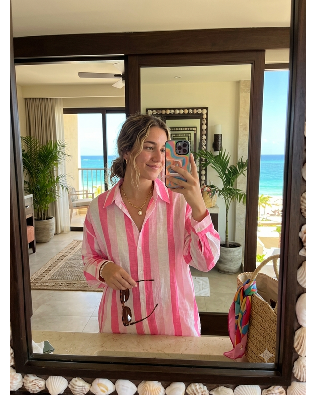 Sagar hill road relaxed cotton shirt with pink and white vertical stripes, worn by a woman in a beach resort mirror.