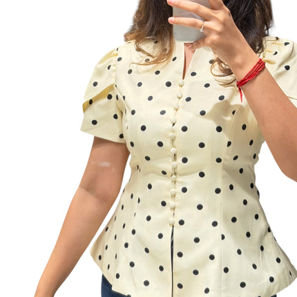 Sagar hill road butter yellow polka dot peplum top with short sleeves and button-front detail worn by a woman