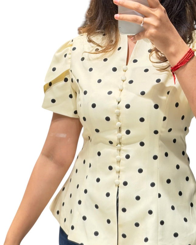 Sagar hill road butter yellow polka dot peplum top with short sleeves and button-front detail worn by a woman