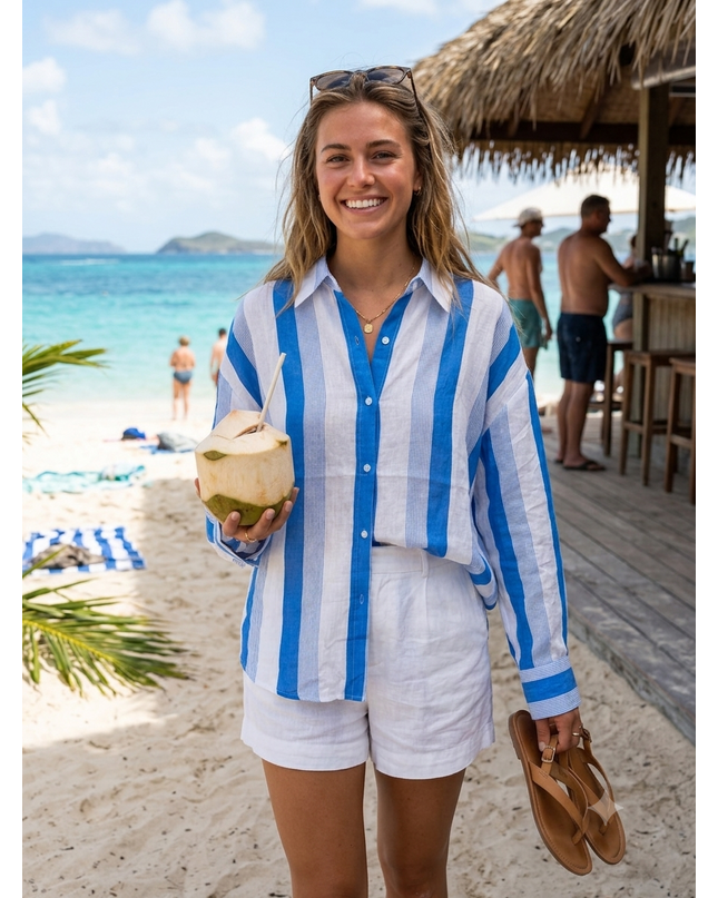 Sagar hill road relaxed cotton shirt with blue vertical stripes, worn by a smiling woman on a sunny beach vacation.